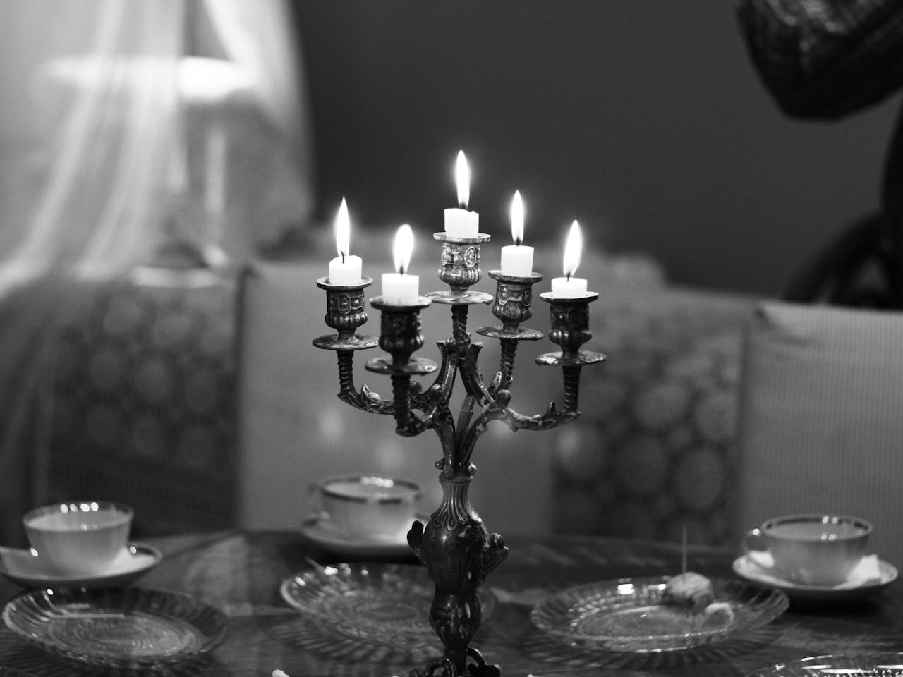A sophisticated black and white image featuring a candlelit dining table with ornate candlesticks and fine tableware.